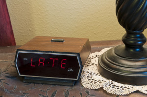 An alarm clock displaying the word "late". This could mean late for work, late for school, late for an appointment or meeting, etc.